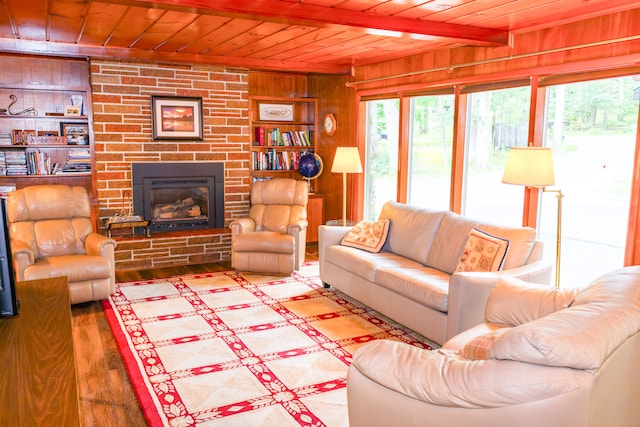 living room featuring wood ceiling, built in shelves, wood-type flooring, a stone fireplace, and wood walls