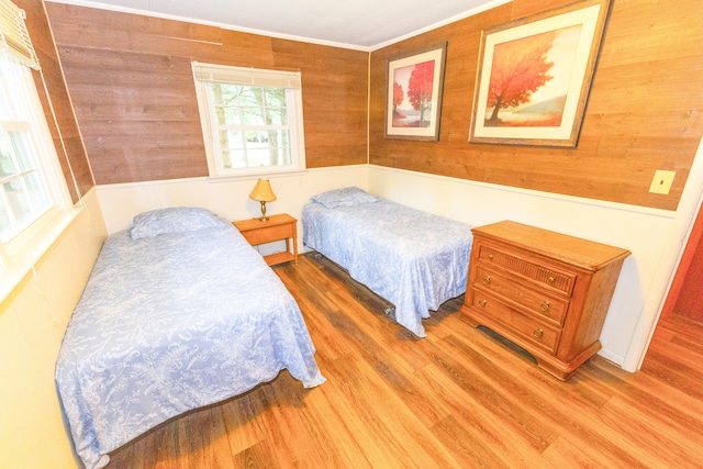 bedroom featuring wood-type flooring, ornamental molding, and wood walls