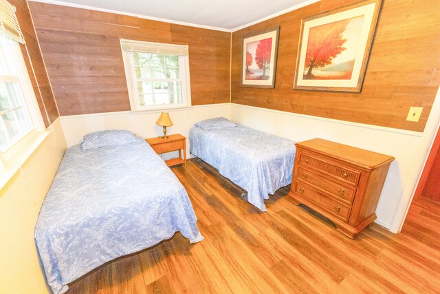 1130 W Higgins Lake Dr, Roscommon, MI 48653 - bedroom featuring wood finished floors, wood walls, and ornamental molding