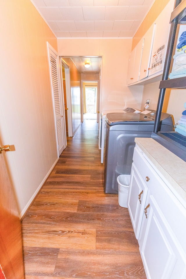 washroom featuring cabinets, dark hardwood / wood-style floors, washer and clothes dryer, and wooden walls