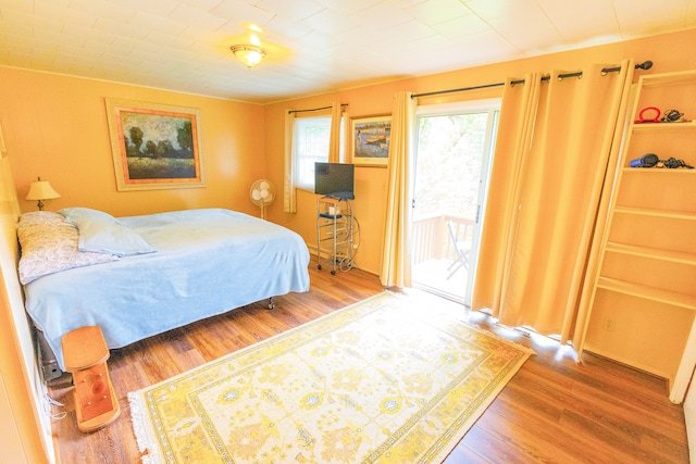 bedroom with access to outside and hardwood / wood-style flooring