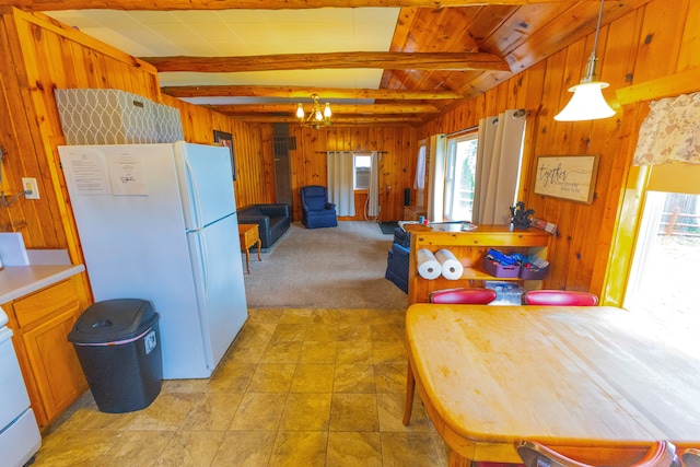 kitchen featuring beamed ceiling, a notable chandelier, white appliances, decorative light fixtures, and wooden walls