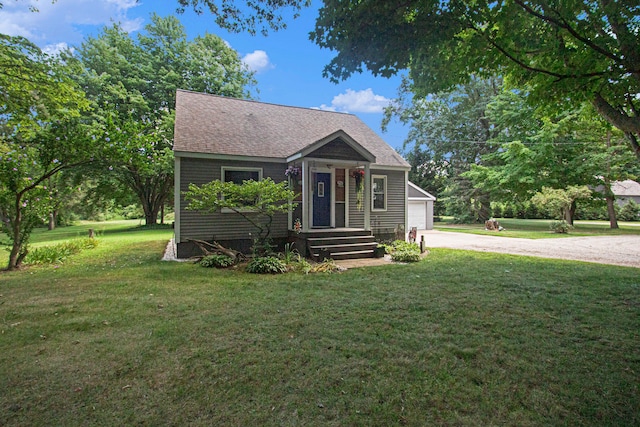 bungalow with a garage, an outdoor structure, and a front yard