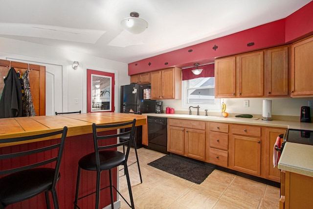 kitchen with black appliances, a kitchen bar, light tile patterned floors, and sink