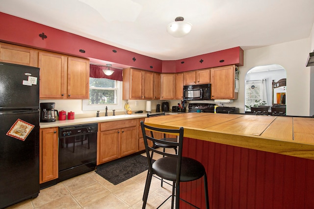 kitchen with black appliances, light tile patterned floors, and sink