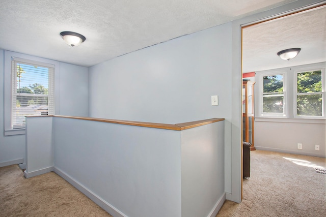 corridor featuring light carpet and a textured ceiling