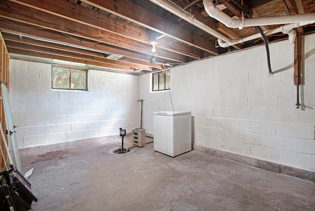 basement featuring a healthy amount of sunlight and fridge