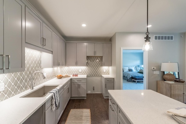637 Woodland Dr, Dexter, MI 48130 - kitchen with gray cabinets, dark wood-style flooring, a sink, pendant lighting, and tasteful backsplash