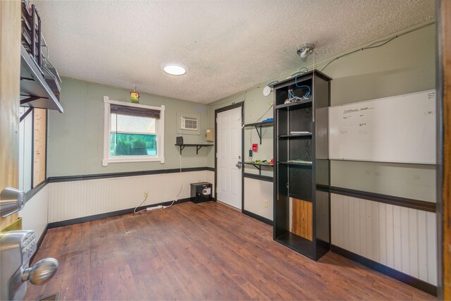 9284 M-35, Gladstone, MI 49837 - empty room with a textured ceiling, wainscoting, and dark wood finished floors