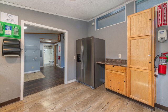 9284 M-35, Gladstone, MI 49837 - kitchen with stainless steel fridge with ice dispenser, light wood-type flooring, crown molding, dark countertops, and baseboards