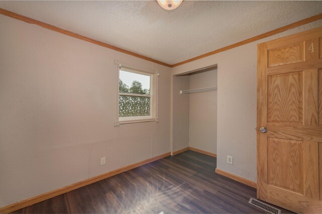 9284 M-35, Gladstone, MI 49837 - unfurnished bedroom featuring dark wood-type flooring, crown molding, a textured ceiling, baseboards, and a closet
