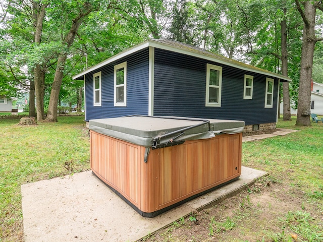 exterior space with a hot tub and a lawn