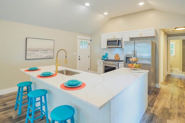 kitchen with stainless steel appliances, sink, a center island with sink, white cabinetry, and lofted ceiling