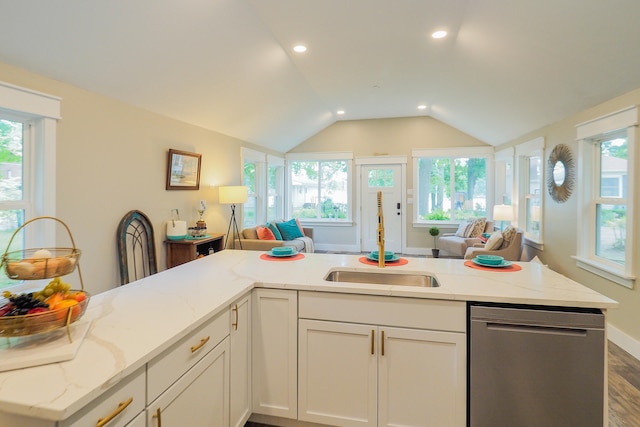 kitchen featuring light stone countertops, stainless steel dishwasher, vaulted ceiling, white cabinets, and hardwood / wood-style flooring