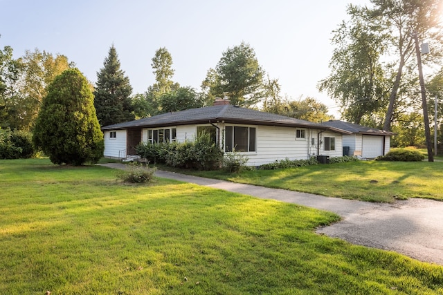 single story home with a garage, cooling unit, and a front yard