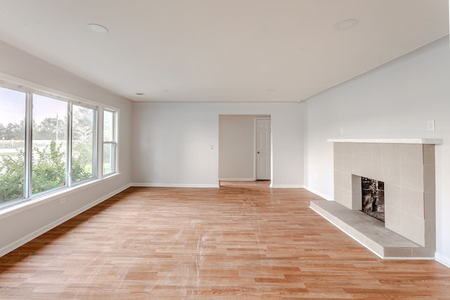 unfurnished living room with light hardwood / wood-style flooring and a tile fireplace