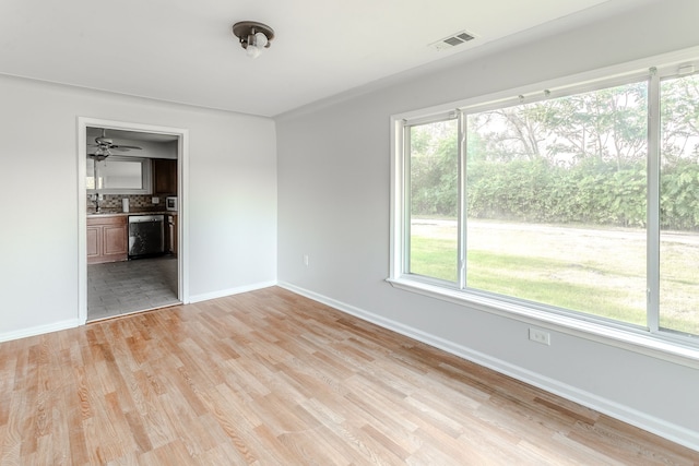 unfurnished room featuring sink, plenty of natural light, and light hardwood / wood-style flooring