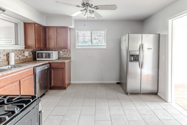 kitchen with appliances with stainless steel finishes, light tile patterned floors, ceiling fan, decorative backsplash, and sink