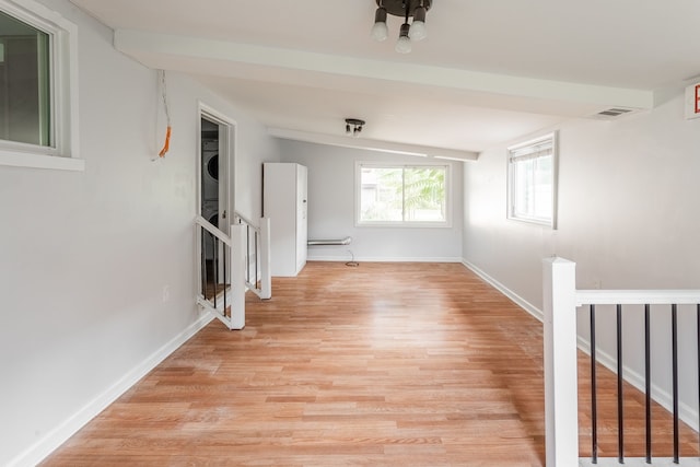 interior space featuring light hardwood / wood-style floors, lofted ceiling, and stacked washer and dryer