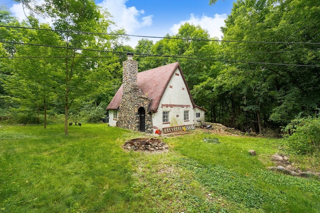 view of side of home with a lawn and an outdoor fire pit