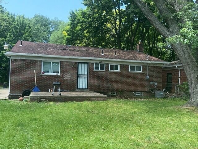 back of house with a patio and a lawn