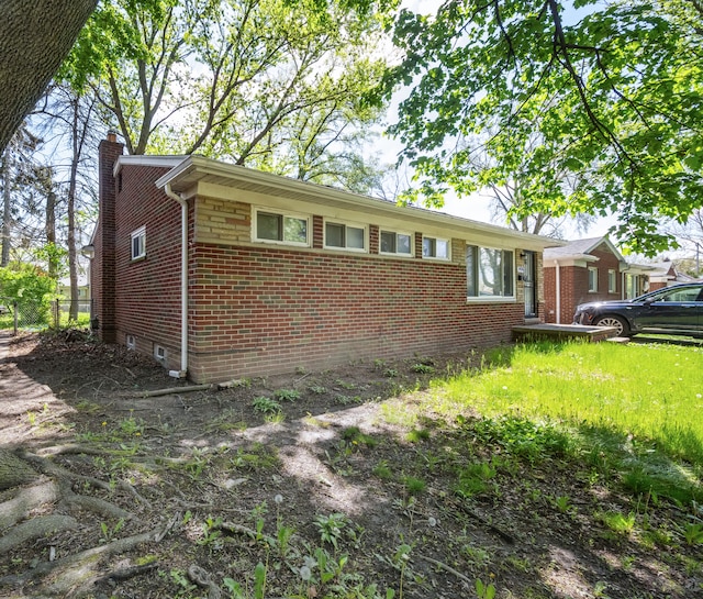 view of side of property featuring a chimney and brick siding