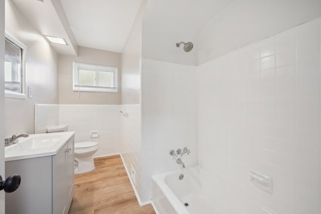 full bathroom with vanity, wood finished floors, toilet, bathing tub / shower combination, and tile walls