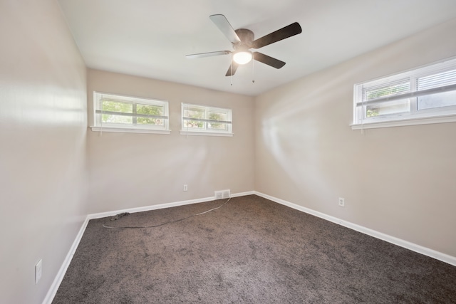 spare room with dark carpet, ceiling fan, and baseboards