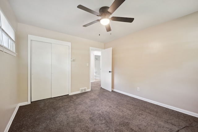 unfurnished bedroom featuring dark colored carpet, baseboards, a closet, and a ceiling fan