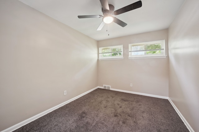 spare room featuring dark carpet, baseboards, and a ceiling fan