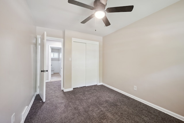 unfurnished bedroom with dark carpet, baseboards, a closet, and a ceiling fan