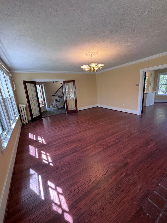 unfurnished living room featuring dark hardwood / wood-style flooring, radiator, ornamental molding, a textured ceiling, and a chandelier