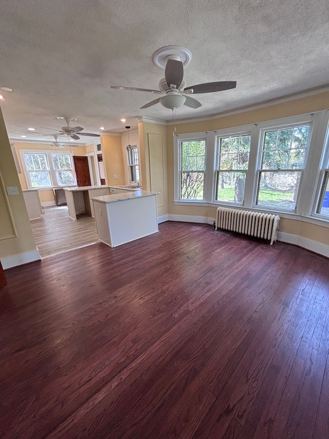 unfurnished living room with a textured ceiling, ceiling fan, radiator heating unit, and dark wood-type flooring