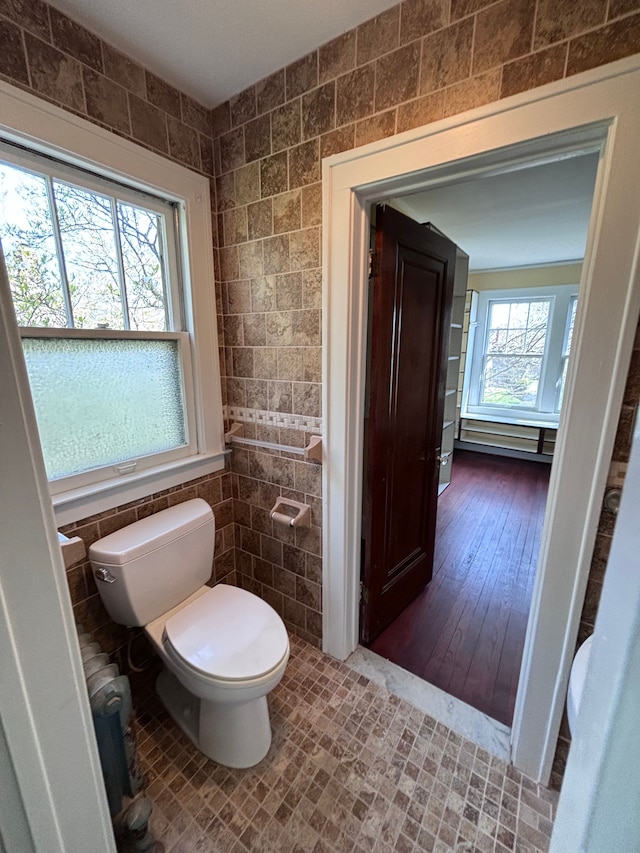 bathroom featuring hardwood / wood-style floors, toilet, and tile walls