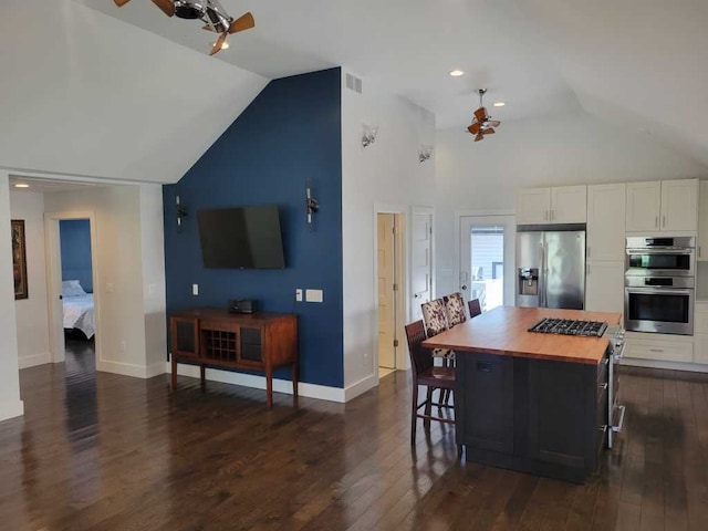 kitchen featuring a breakfast bar, stainless steel appliances, white cabinets, dark hardwood / wood-style floors, and a kitchen island