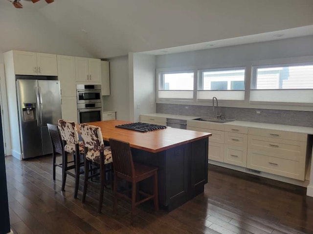 kitchen with plenty of natural light, white cabinetry, stainless steel appliances, and lofted ceiling