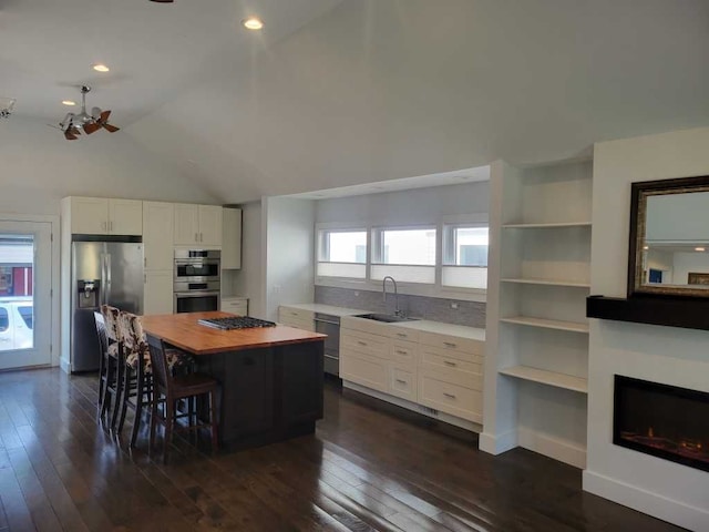 kitchen with white cabinetry, sink, stainless steel appliances, dark hardwood / wood-style floors, and a kitchen island