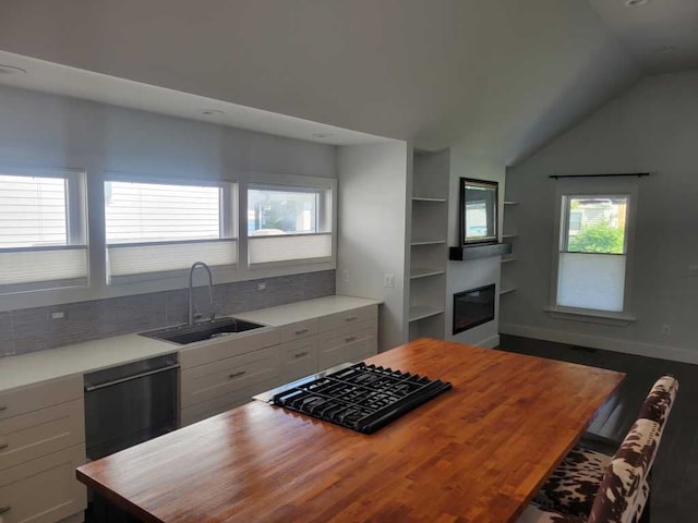 kitchen with sink, butcher block countertops, vaulted ceiling, white cabinets, and black appliances