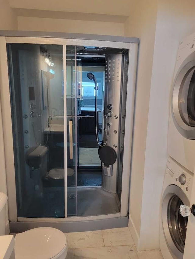 bathroom featuring a shower, toilet, and stacked washer and clothes dryer