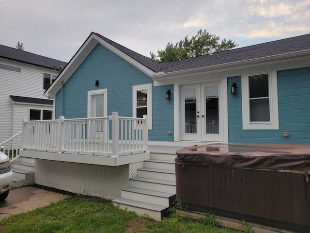 rear view of house with a deck, french doors, and a hot tub