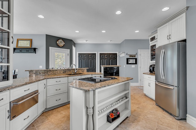 kitchen with white cabinets, a center island, stainless steel fridge, and black cooktop