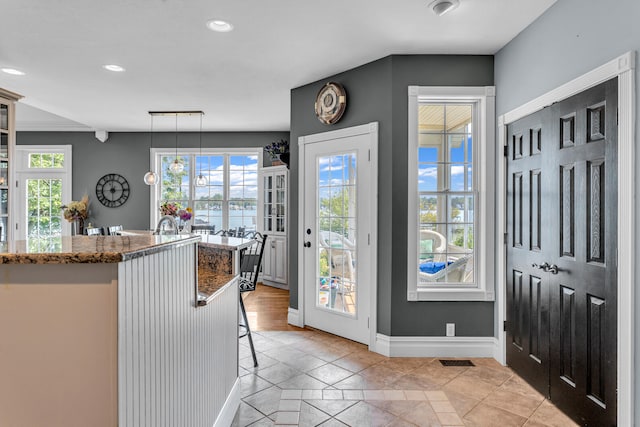 kitchen with stone counters, a kitchen breakfast bar, decorative light fixtures, and light tile patterned flooring