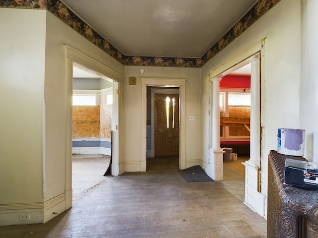 corridor with wood-type flooring and decorative columns