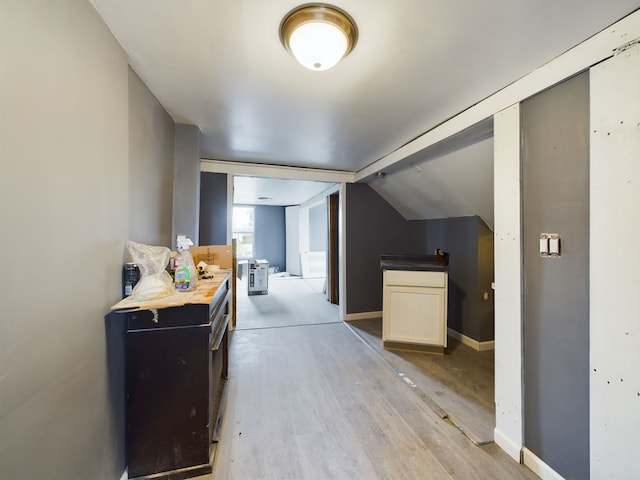 corridor featuring light hardwood / wood-style flooring and vaulted ceiling