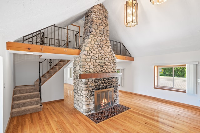 1794 S Hughes Rd, Brighton, MI 48114 - unfurnished living room featuring wood finished floors, high vaulted ceiling, a fireplace, and stairs