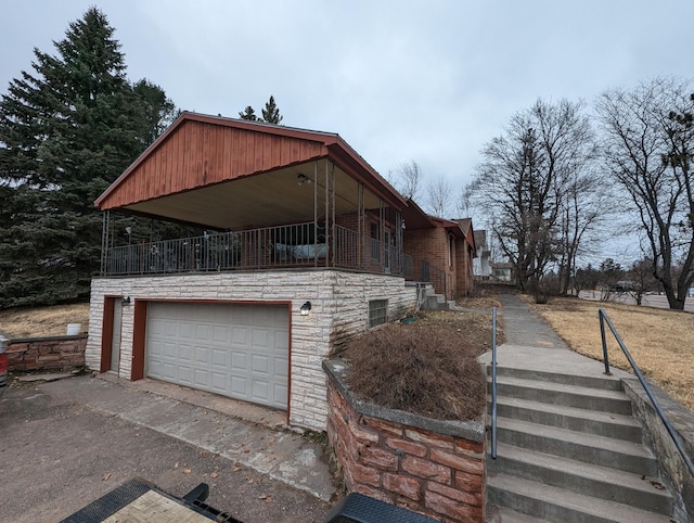 42294 Willson Memorial Dr, Chassell, MI 49916 - view of property exterior with stone siding, an attached garage, driveway, and stairs