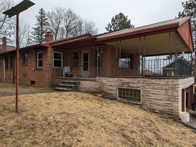 42294 Willson Memorial Dr, Chassell, MI 49916 - view of front of house featuring a front yard, a chimney, brick siding, and metal roof