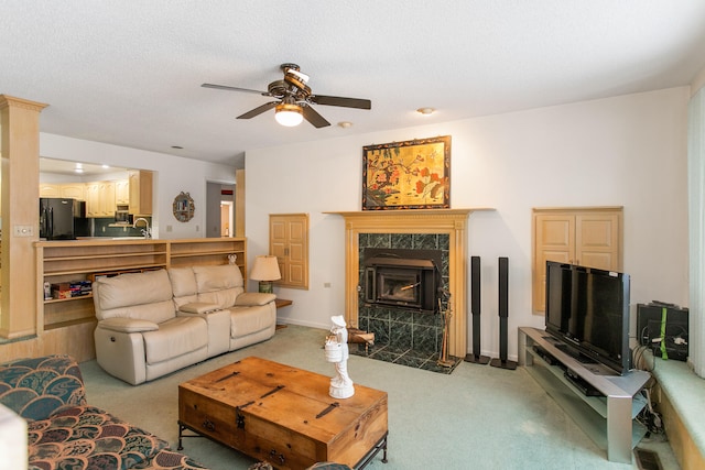 carpeted living room with a high end fireplace, a textured ceiling, ceiling fan, and sink