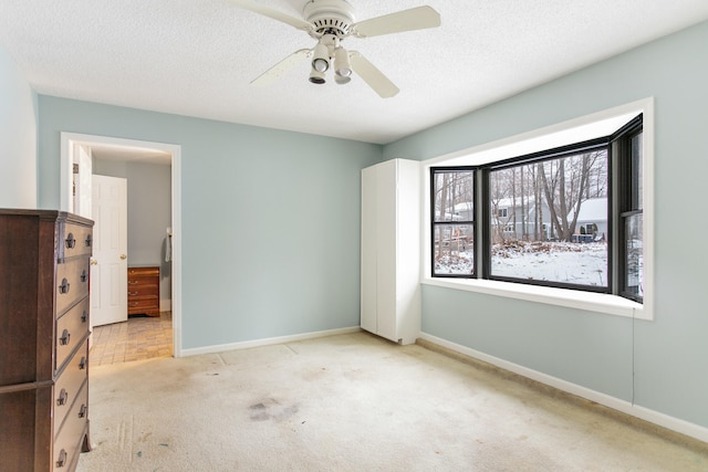 unfurnished bedroom with a textured ceiling, ceiling fan, and light carpet