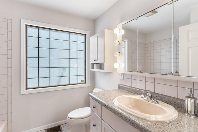 bathroom featuring vanity, backsplash, toilet, and a wealth of natural light